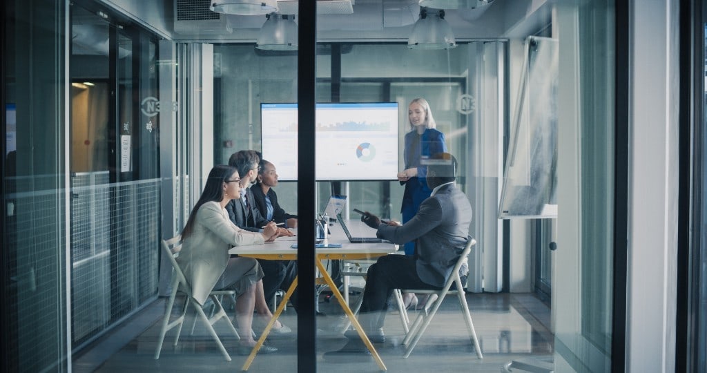 A team reviewing results together in a glass meeting room.